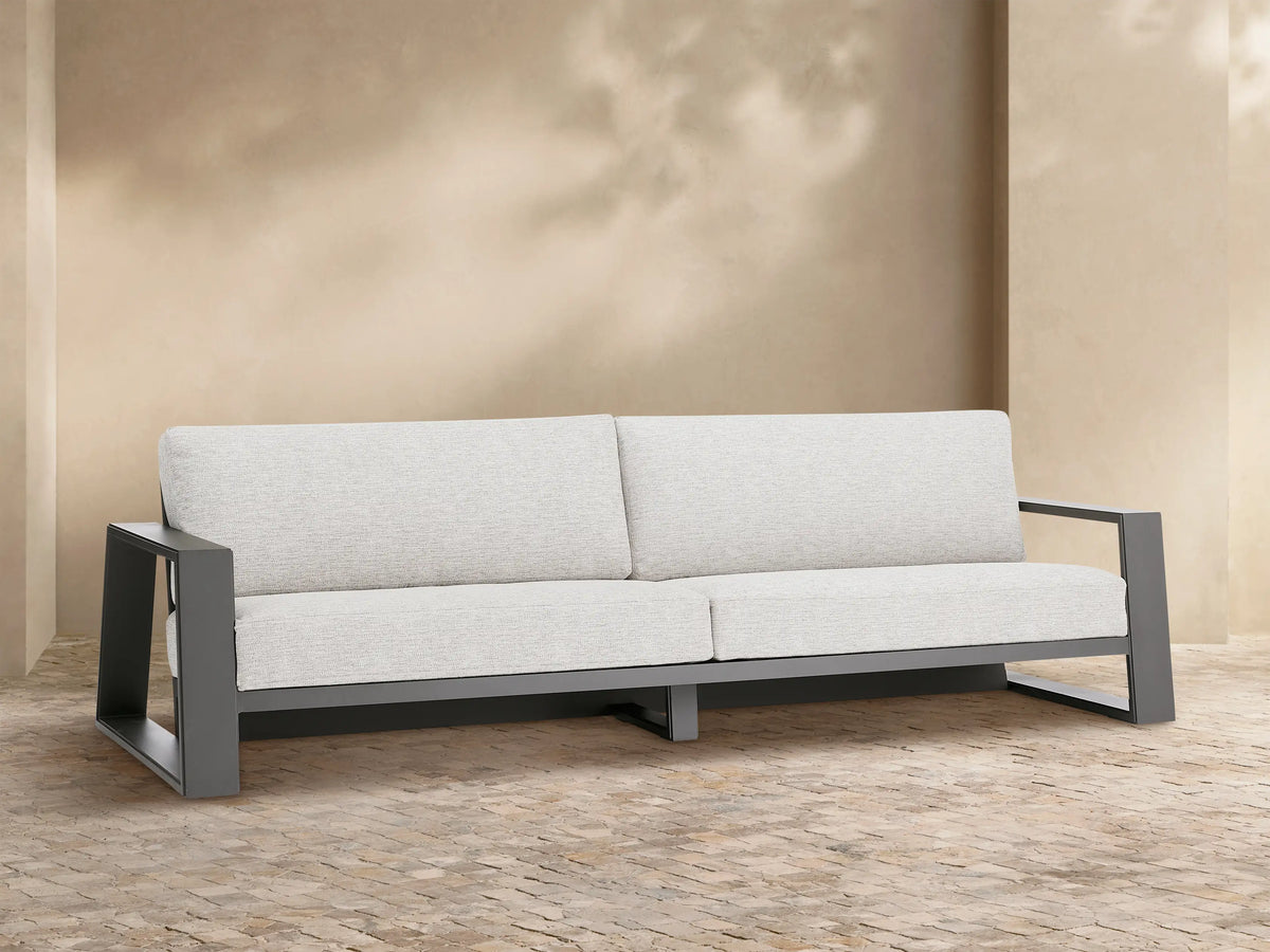 Canyon Outdoor Aluminum Sofa, two-seater, with a dark gray frame and light gray cushions on a patio setting.