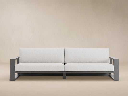 Canyon Outdoor Aluminum Sofa, two-seater, with a dark gray frame and light gray cushions on a patio setting.