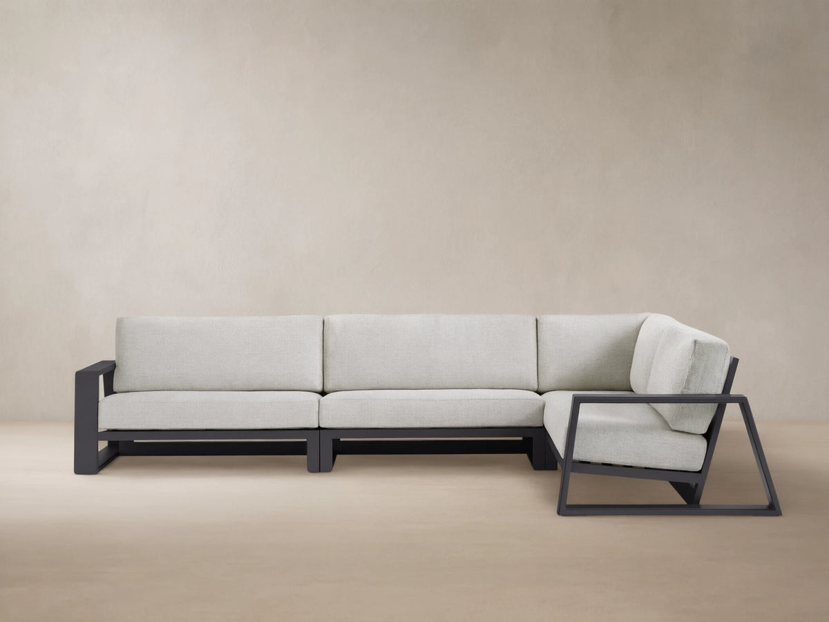 Modern L-shaped Canyon Outdoor Aluminum Three-Piece Sectional with dark gray frame & light gray cushions, on a patterned patio.