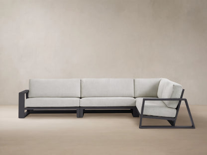 Modern L-shaped Canyon Outdoor Aluminum Three-Piece Sectional with dark gray frame & light gray cushions, on a patterned patio.