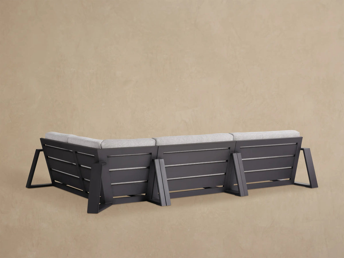 Canyon Outdoor Aluminum Three-Piece Sectional. Close-up of light gray textured cushions on a dark aluminum frame, viewed from above.
