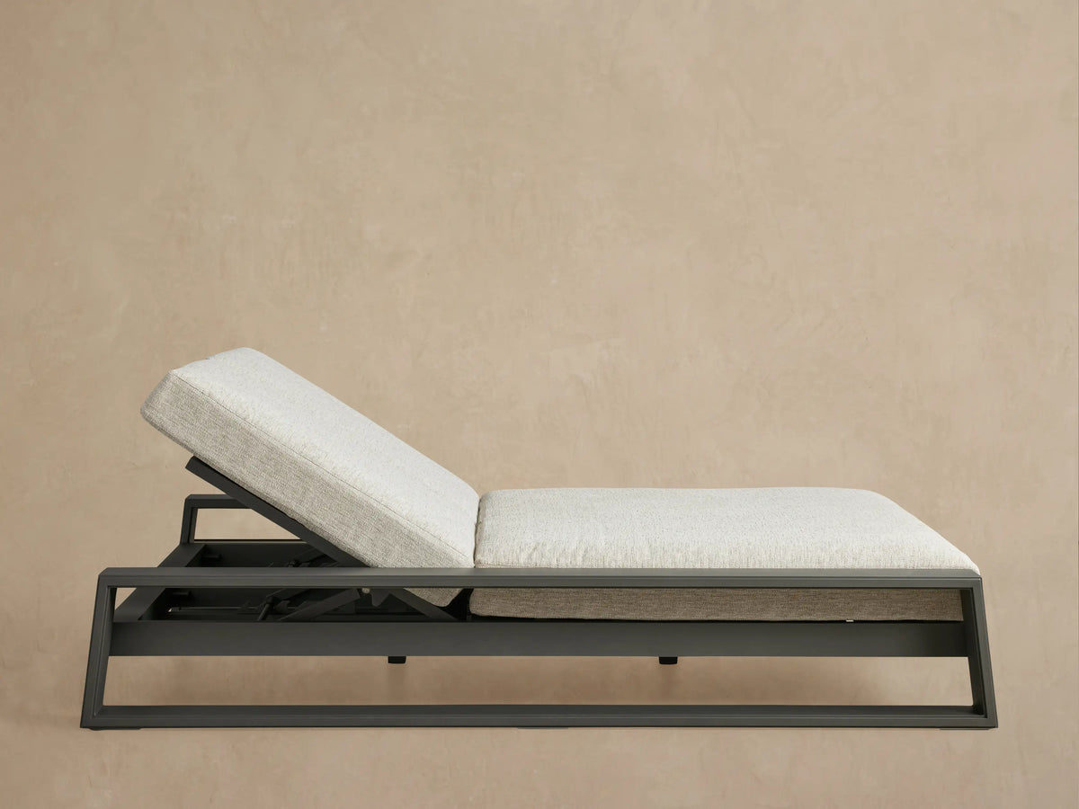 Canyon Outdoor Aluminum Double Chaise with angled backrests, dark gray frame, and light gray cushions on a patio.