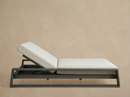 Canyon Outdoor Aluminum Double Chaise with angled backrests, dark gray frame, and light gray cushions on a patio.