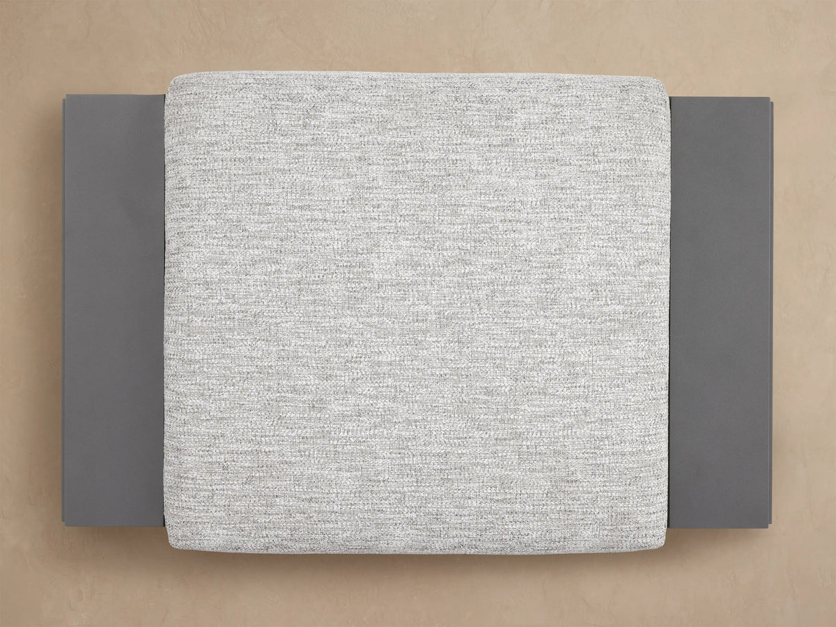 Canyon Outdoor Aluminum Ottoman, featuring a light gray textured cushion resting on a dark gray, powder-coated aluminum frame.