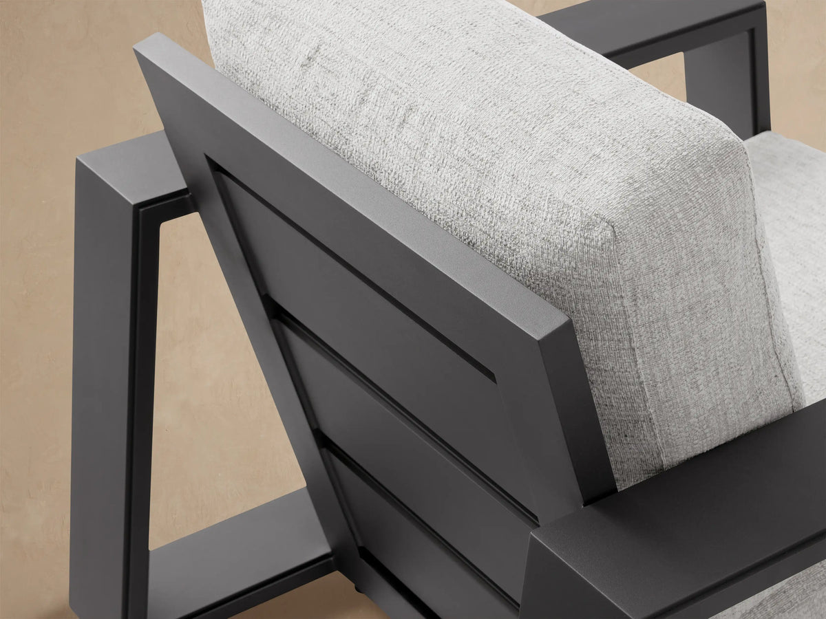 Front view of Canyon Outdoor Aluminum Swivel Chair with dark gray frame and light gray cushions, on a stone patio.