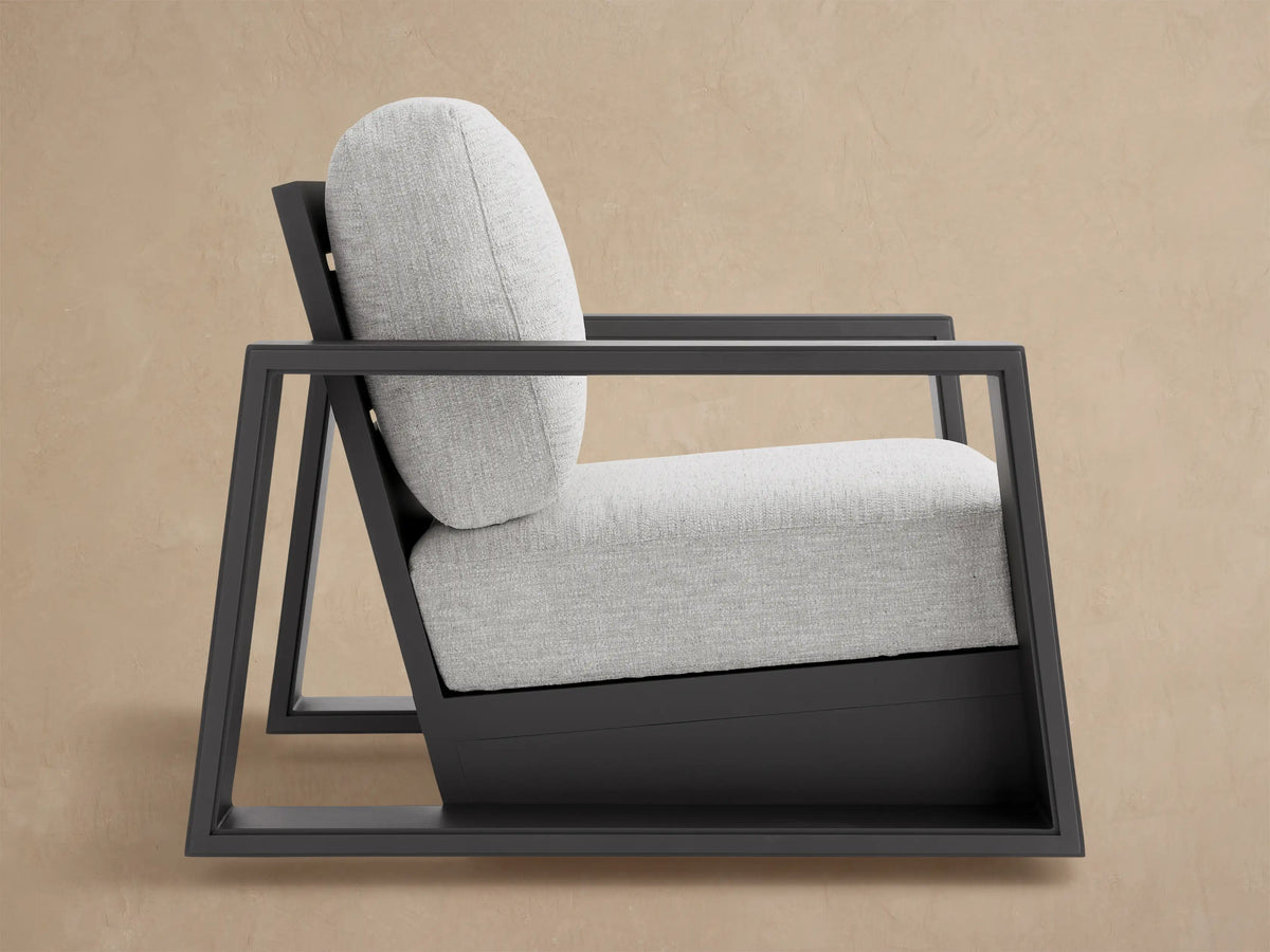 Close-up of Canyon Outdoor Aluminum Swivel Chair's dark gray frame and light gray textured cushion, angled from behind.