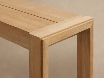 Light natural wood Canyon Outdoor Teak Dining Bench with sturdy rectangular legs, shown at a slight angle against a light background.