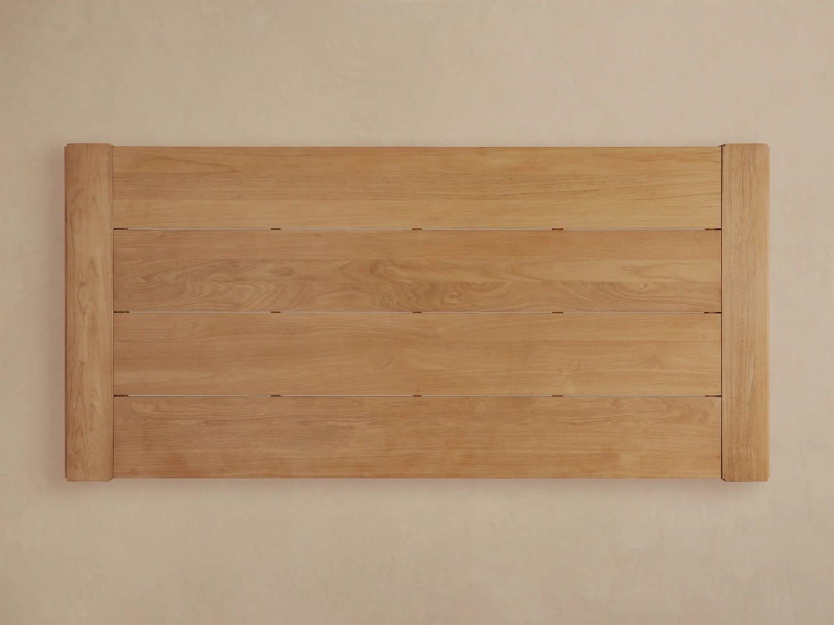 Close-up of Canyon Outdoor Teak Dining Table corner showing light brown planks, visible wood grain, and sturdy frame.