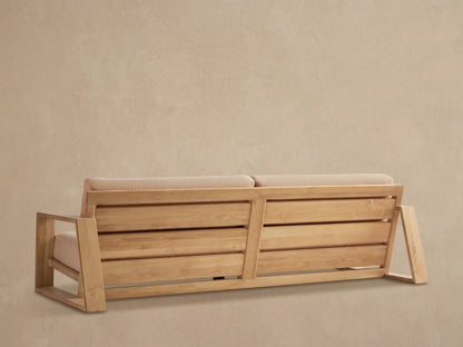 Angled close-up of Canyon Outdoor Teak Sofa. Light teak wood frame with armrest & back slats, tan textured fabric cushions.