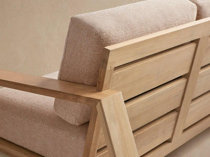 Canyon Outdoor Teak Sofa with light teak wood frame, two seats, and beige textured cushions, on a stone patio.