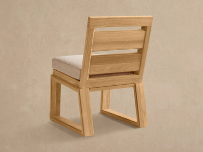 Canyon Outdoor Teak Dining Side Chair: Close-up of angled light brown teak wood frame, slatted back, and textured beige cushion.