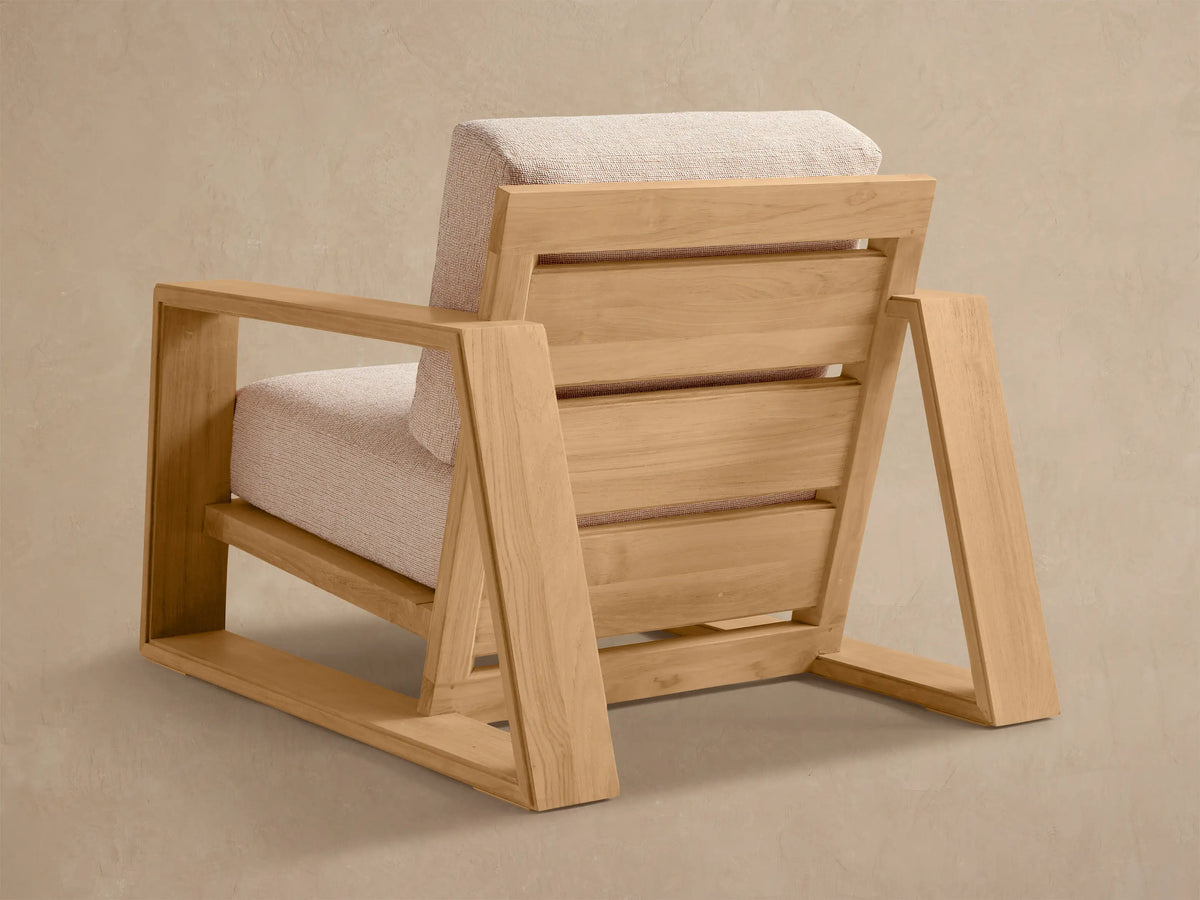 Close-up, angled view of Canyon Outdoor Teak Lounge Chair. Light teak wood frame with light, textured back and seat cushions.