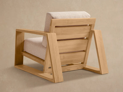 Close-up, angled view of Canyon Outdoor Teak Lounge Chair. Light teak wood frame with light, textured back and seat cushions.