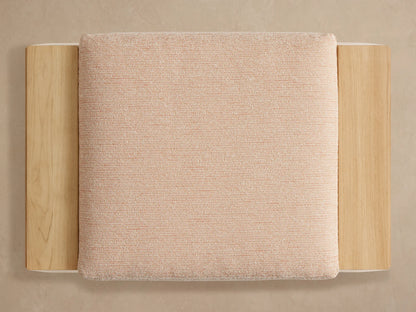 Close-up of a Canyon Outdoor Teak Ottoman. Light natural teak wood frame, woven light beige cushion with subtle orange threads.