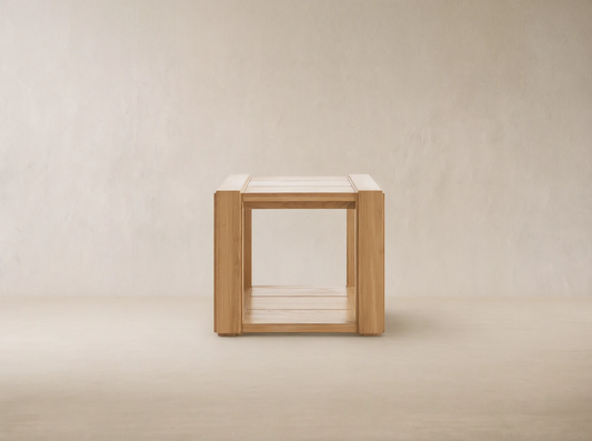 Canyon Outdoor Teak End Table, light natural teak wood, square with slatted top and bottom, on a stone patio.