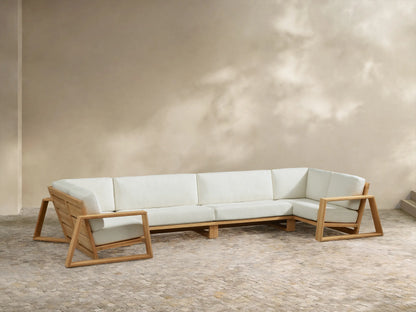 Canyon Outdoor Teak 4-Piece Sectional: U-shaped light teak wood frame, thick cream cushions on a stone patio.