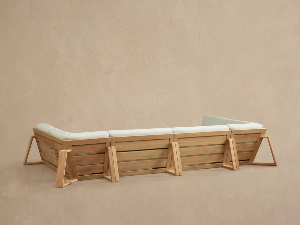 Close-up of Canyon Outdoor Teak Four-Piece Sectional, showing natural teak frame and plush cream cushions from a corner view.