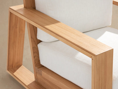 Front view of Canyon Outdoor Teak Swivel Chair with light brown teak wood frame, thick white cushions on a stone patio.