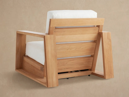 Close-up of Canyon Outdoor Teak Swivel Chair showing the smooth, angular teak armrest and bright white, textured cushions.
