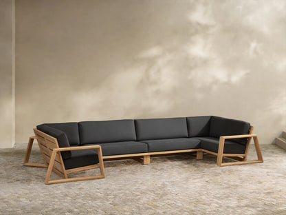 U-shaped Canyon Outdoor Teak Four-Piece Sectional with natural teak frame & dark grey cushions on a light-tiled patio.