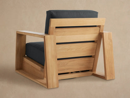 Angled close-up of the Canyon Outdoor Teak Swivel Chair, highlighting its light natural teak wood armrest and dark gray cushions.