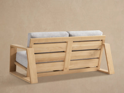Close-up of Canyon Outdoor Teak Sofa, showing its light brown teak wood frame and light grey fabric cushions.