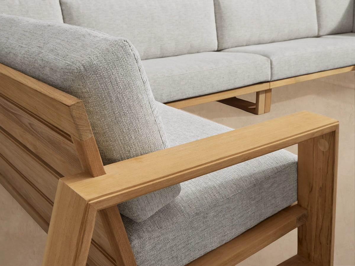 Canyon Outdoor Teak Four-Piece Sectional, L-shaped, with light grey cushions on natural teak wood frame outdoors.