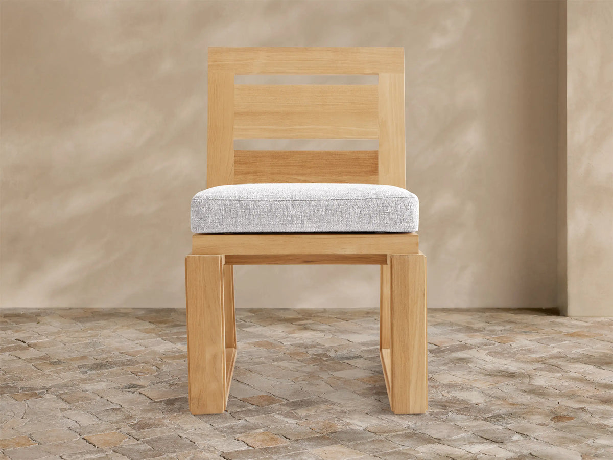 Canyon Outdoor Teak Dining Side Chair, light-toned teak frame, slatted back, sturdy block-style legs, and light grey cushion.