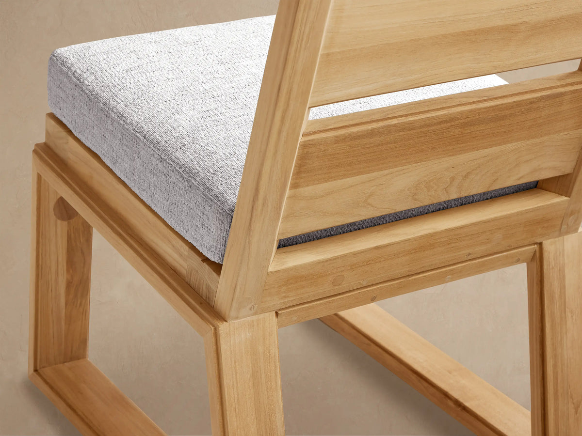 Front view Canyon Outdoor Teak Dining Side Chair, natural teak wood frame with slatted back, light gray cushion.