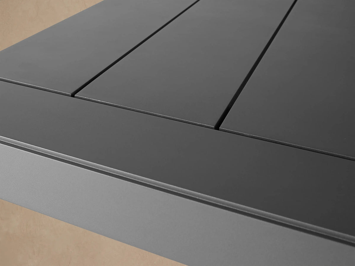 Canyon Outdoor Aluminum Dining Table, dark gray rectangular with sturdy, thick legs, on a light paver patio.