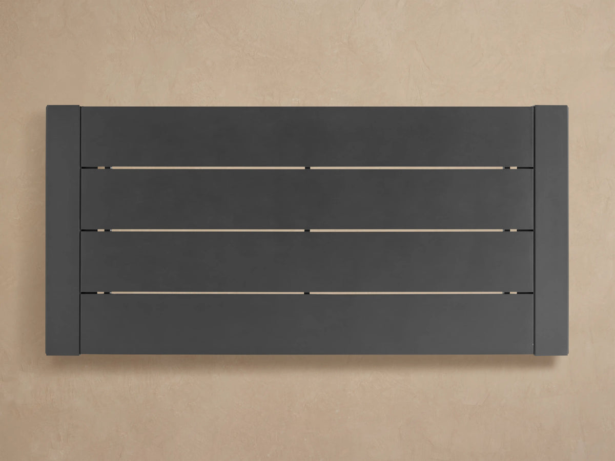 Angled close-up of dark gray Canyon Outdoor Aluminum Dining Table's matte slat top and sturdy side edge.