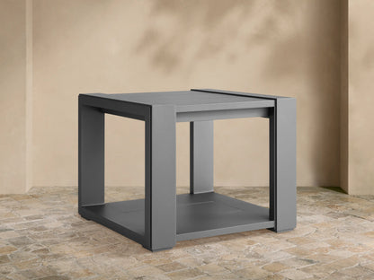 Dark grey square Canyon Outdoor End Table, aluminum with slat top & bottom shelf, on a stone patio.