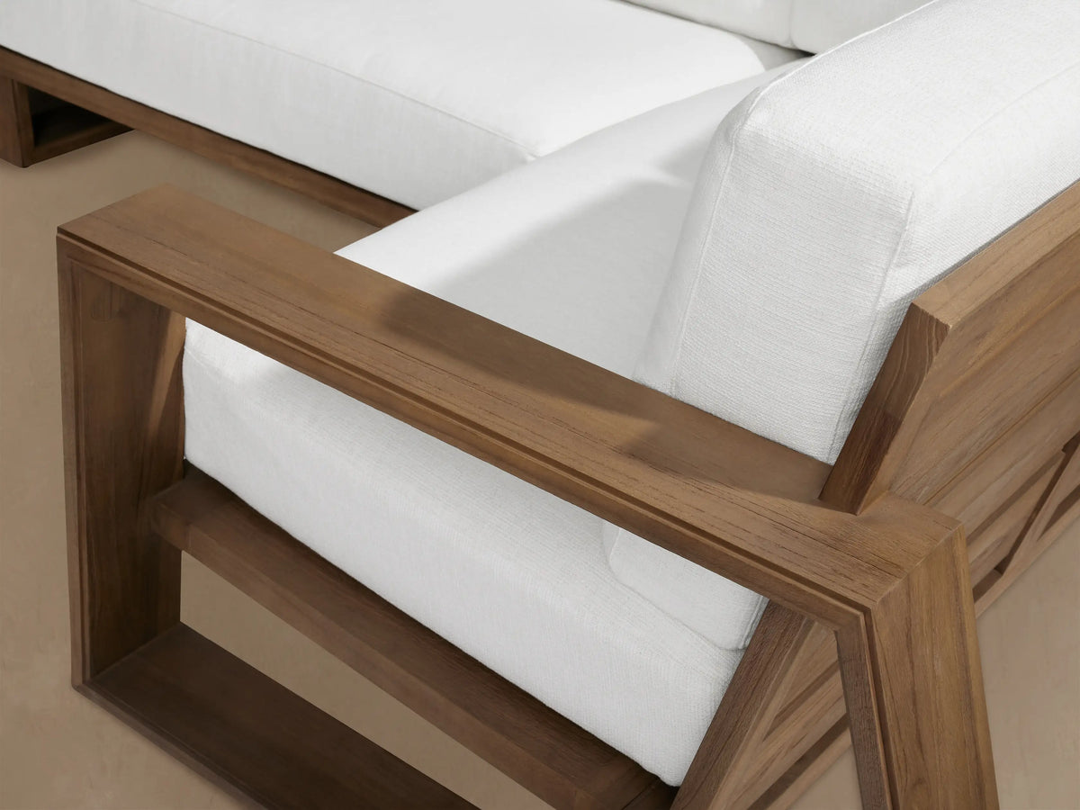 Canyon Outdoor Teak Four-Piece Sectional: L-shaped sofa, two armchairs with natural wood frames & white cushions.