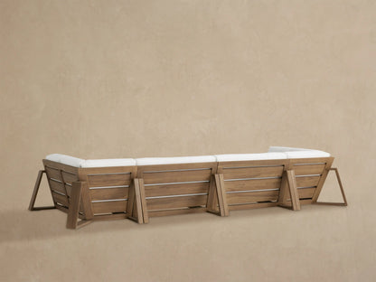 Close-up of Canyon Outdoor Teak Sectional corner; angular brown teak frame supports plump white seat and back cushions.