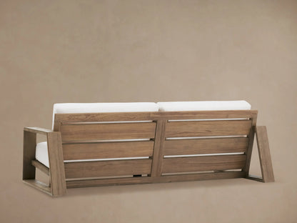 Canyon Outdoor Teak Sofa armrest in light brown distressed teak wood, with visible grain and plush white outdoor cushions.