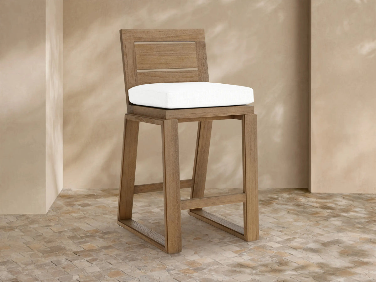 Canyon Outdoor Teak Barstool angled right: light brown teak with square back, white cushion, sturdy legs on mosaic tile.