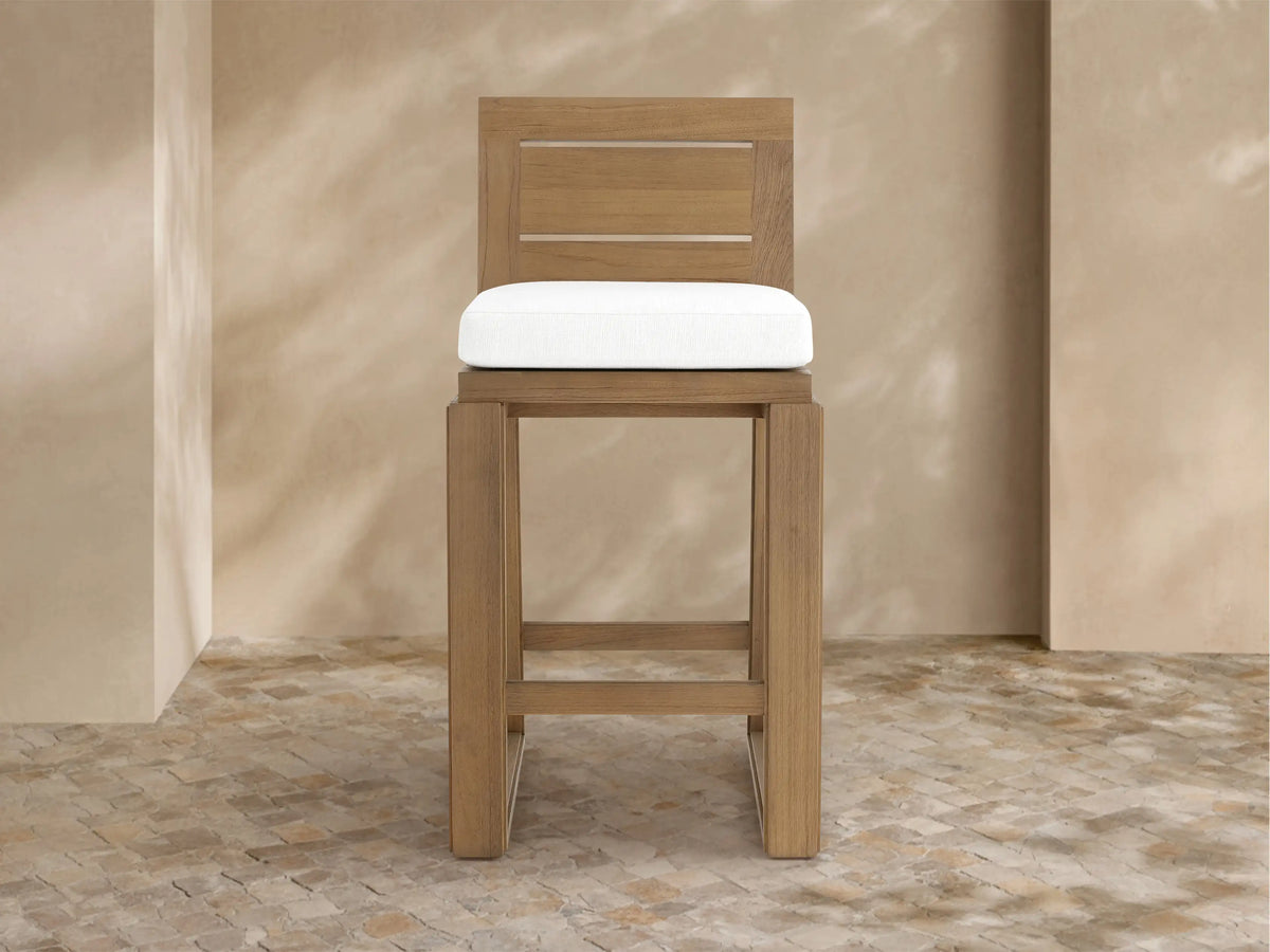Canyon Outdoor Teak Barstool angled right: light brown teak with square back, white cushion, sturdy legs on mosaic tile.