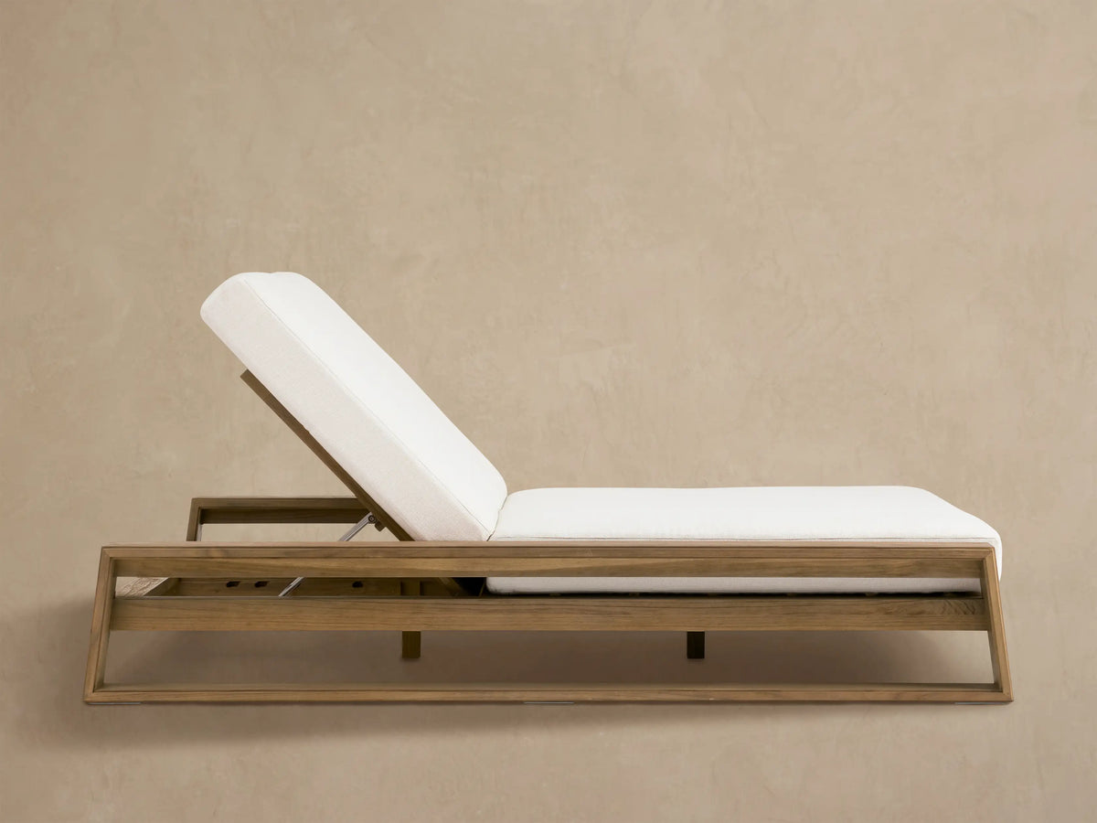Canyon Outdoor Teak Double Chaise with light brown wood frame & white cushions. Backrests slightly raised, on a patio.