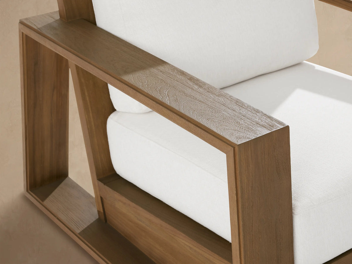 Canyon Outdoor Teak Swivel Chair. Front view of chair with natural teak wood frame, wide arms, and white cushions.