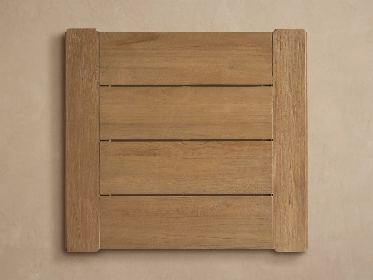 Close-up of a Canyon Outdoor Teak Bar Table corner, showing light-colored, wire-brushed teak wood with visible grain.