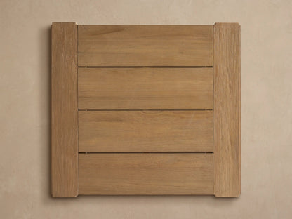 Close-up of a Canyon Outdoor Teak Bar Table corner, showing light-colored, wire-brushed teak wood with visible grain.