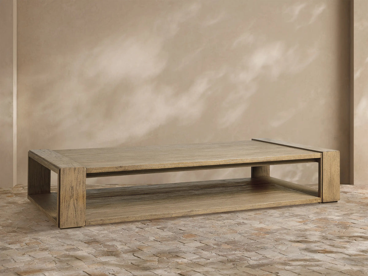 Canyon Outdoor Teak Coffee Table: Rectangular, light brown distressed teak wood with top and lower shelf, on a stone floor.
