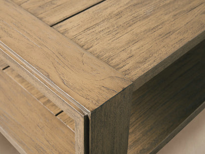 Rectangular light brown distressed teak Canyon Outdoor Coffee Table with two tiers, angled on a stone patio.