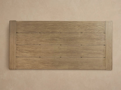Close-up of a weathered light brown Canyon Outdoor Teak Dining Table corner, showing plank details and wood grain.