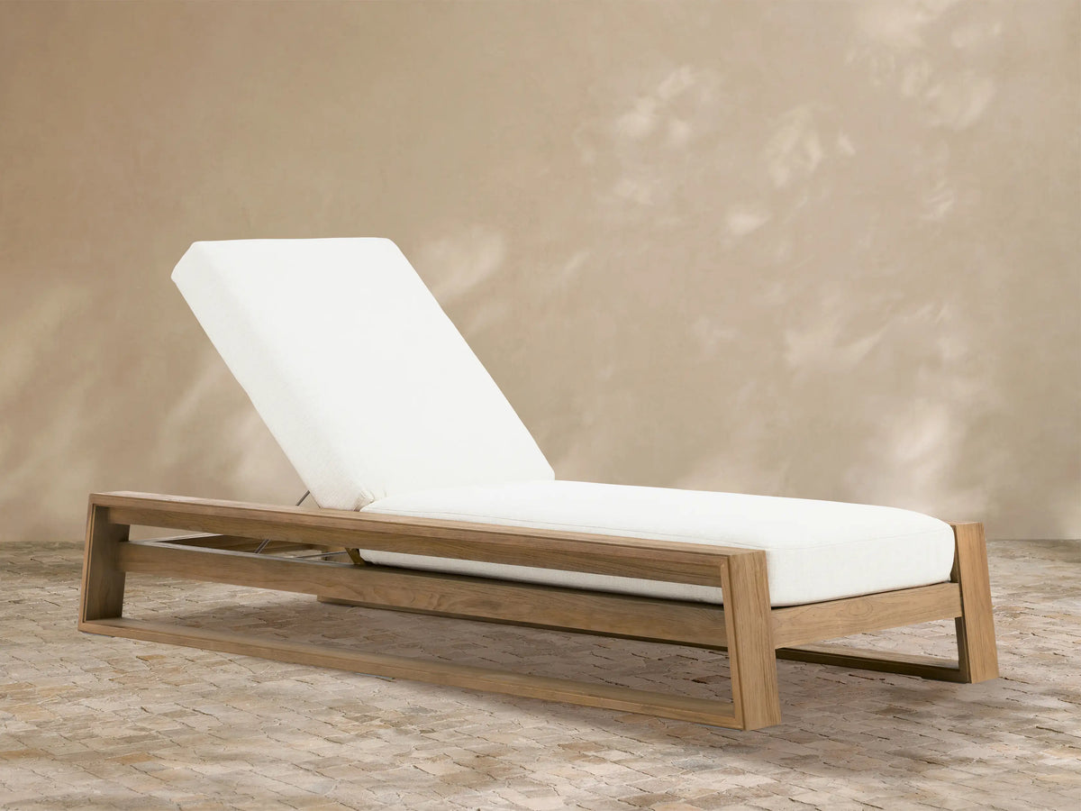 Canyon Weathered Fawn Outdoor Teak Chaise with white Eden Snow cushions, back elevated, on a light stone patio.