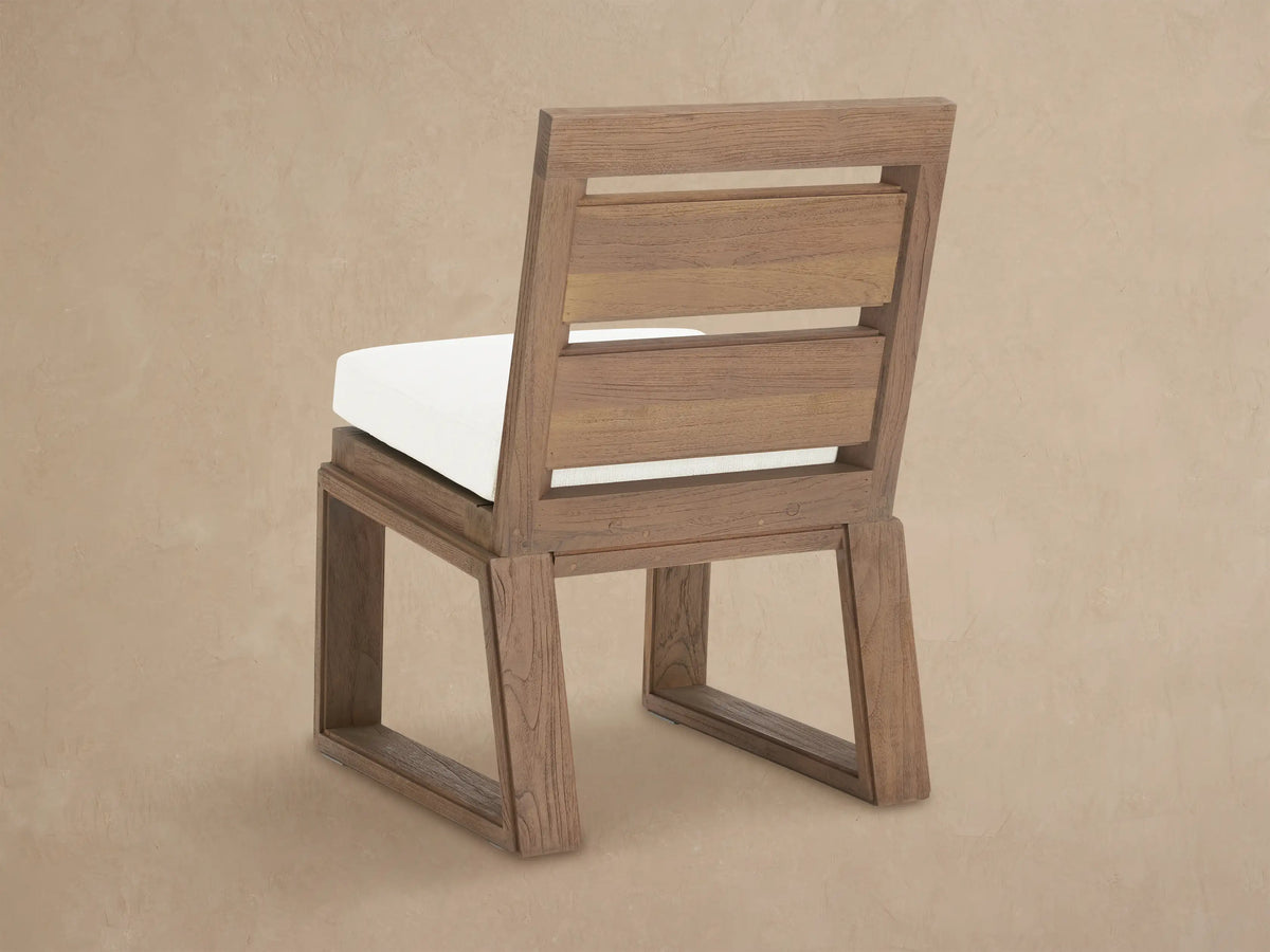 Close-up of Canyon Outdoor Teak Dining Side Chair; weathered teak frame with visible grain, bright white Eden Snow cushion.