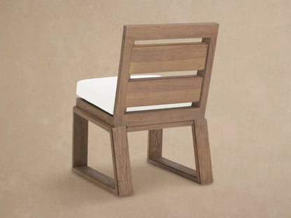 Close-up of Canyon Outdoor Teak Dining Side Chair; weathered teak frame with visible grain, bright white Eden Snow cushion.