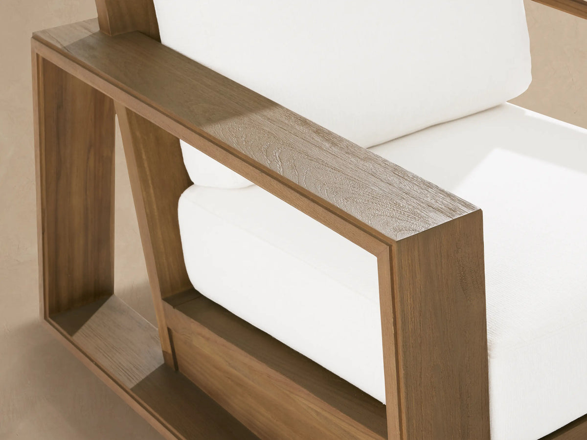 Canyon Outdoor Teak Lounge Chair, front. Blocky brown teak frame with subtly distressed armrests, plush white cushions.