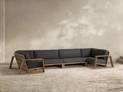 Canyon Outdoor Teak Four-Piece Sectional with dark gray cushions & natural teak frame on a stone patio.