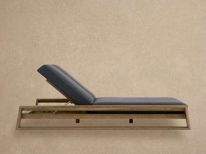Canyon Outdoor Teak Double Chaise with natural teak wood frame & dark gray cushions, backrests raised, on a stone patio.